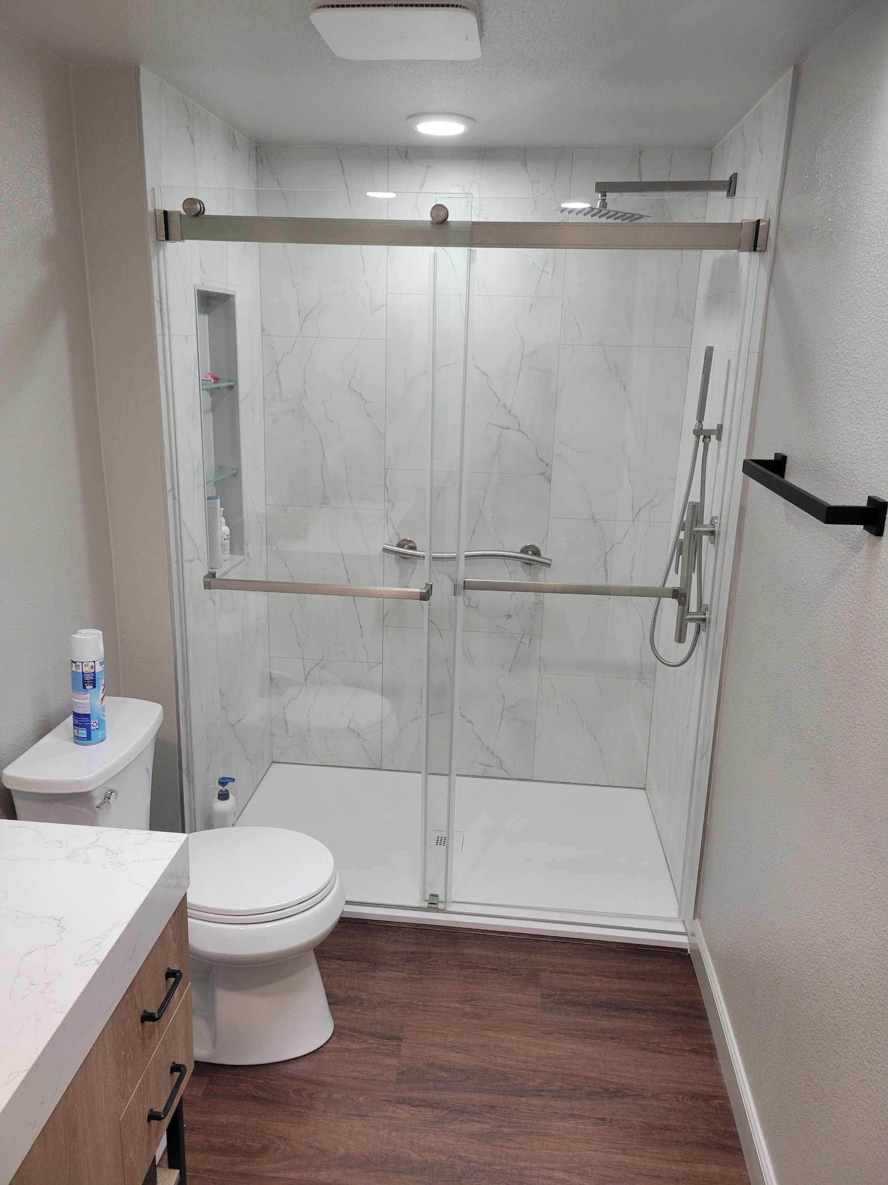 Completed bathroom remodel with marble shower enclosure and modern finishes